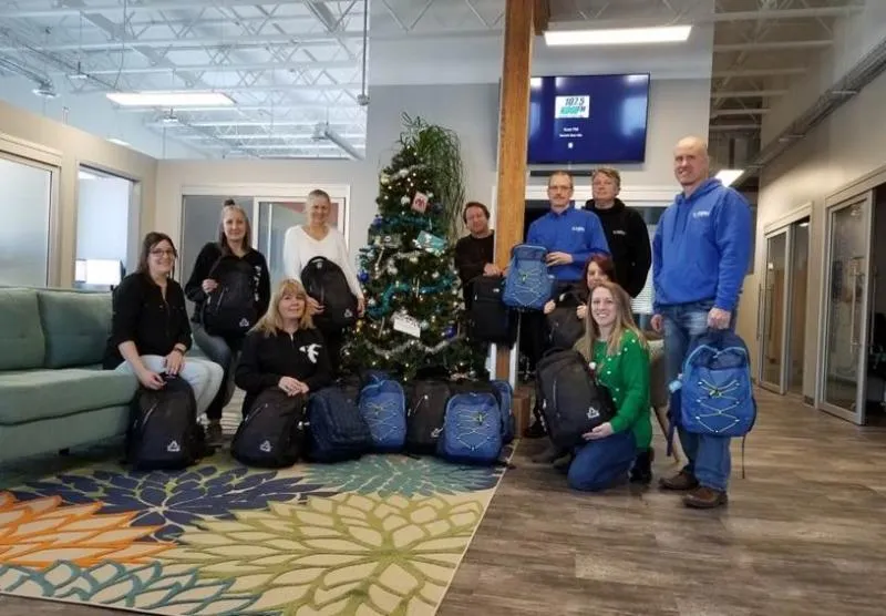 CSOLVE team members gathered with Holiday Helpers backpacks in the office